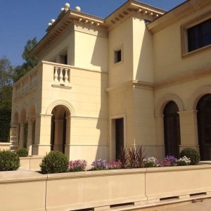 A stone villa style home is shown. The whole house has a facade of stone with extra detailing around the windows and doors.