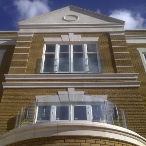 Stone detail is shown on the front of a house. There are decorative stone window headers, a stone band across the top of a balcony area and a stone roof detail.