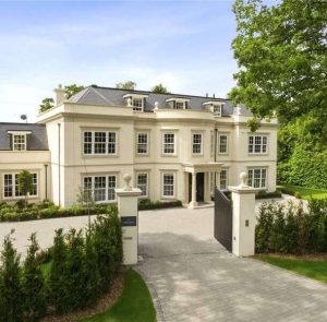 Light coloured mansion style house with a gated front.
